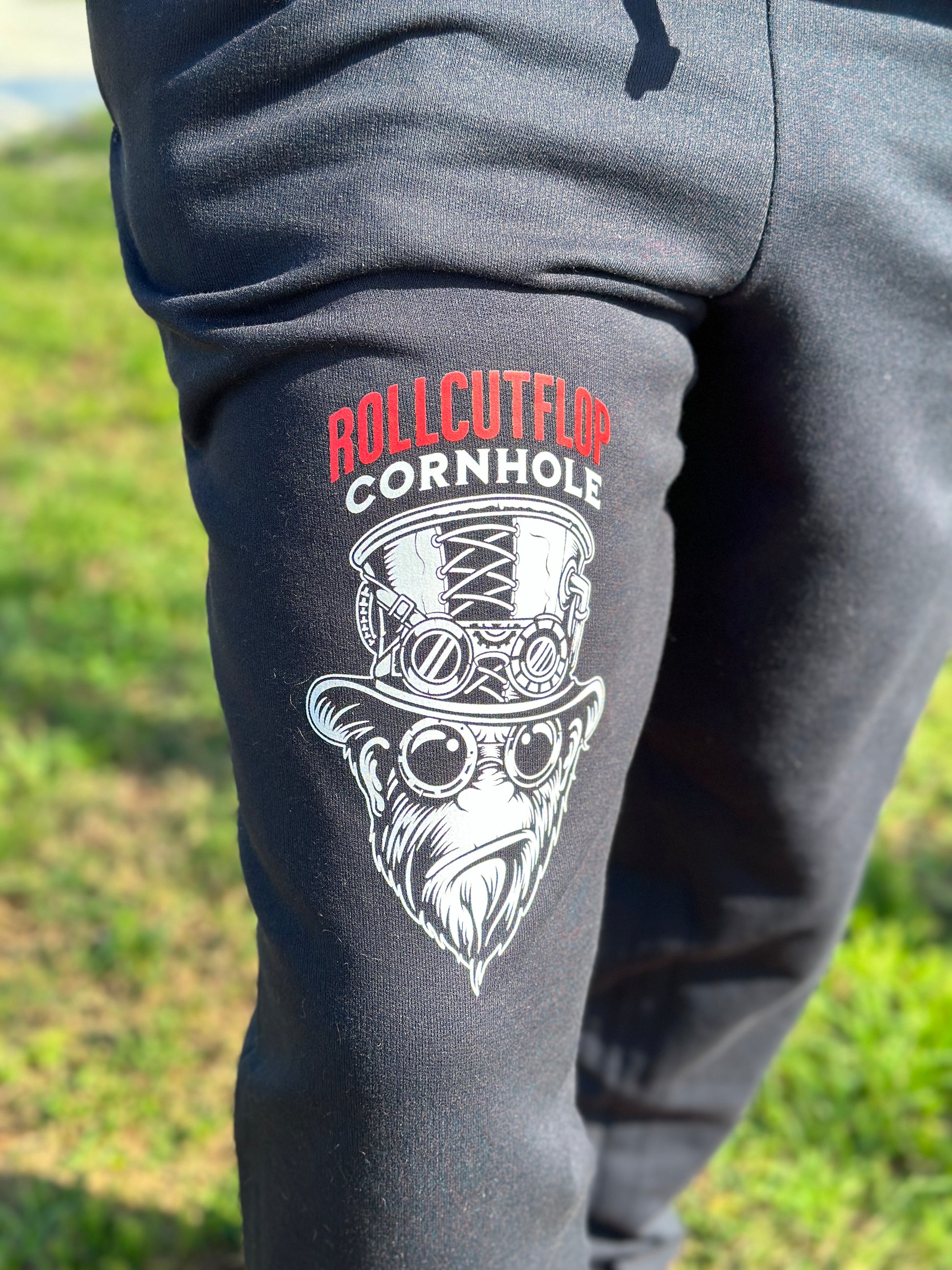 Close up of right leg and logo of Roll Cut Flop Cornhole™ Unisex Nublend® Black Jogger Sweatpants- Steampunk Gorilla Face & Gears