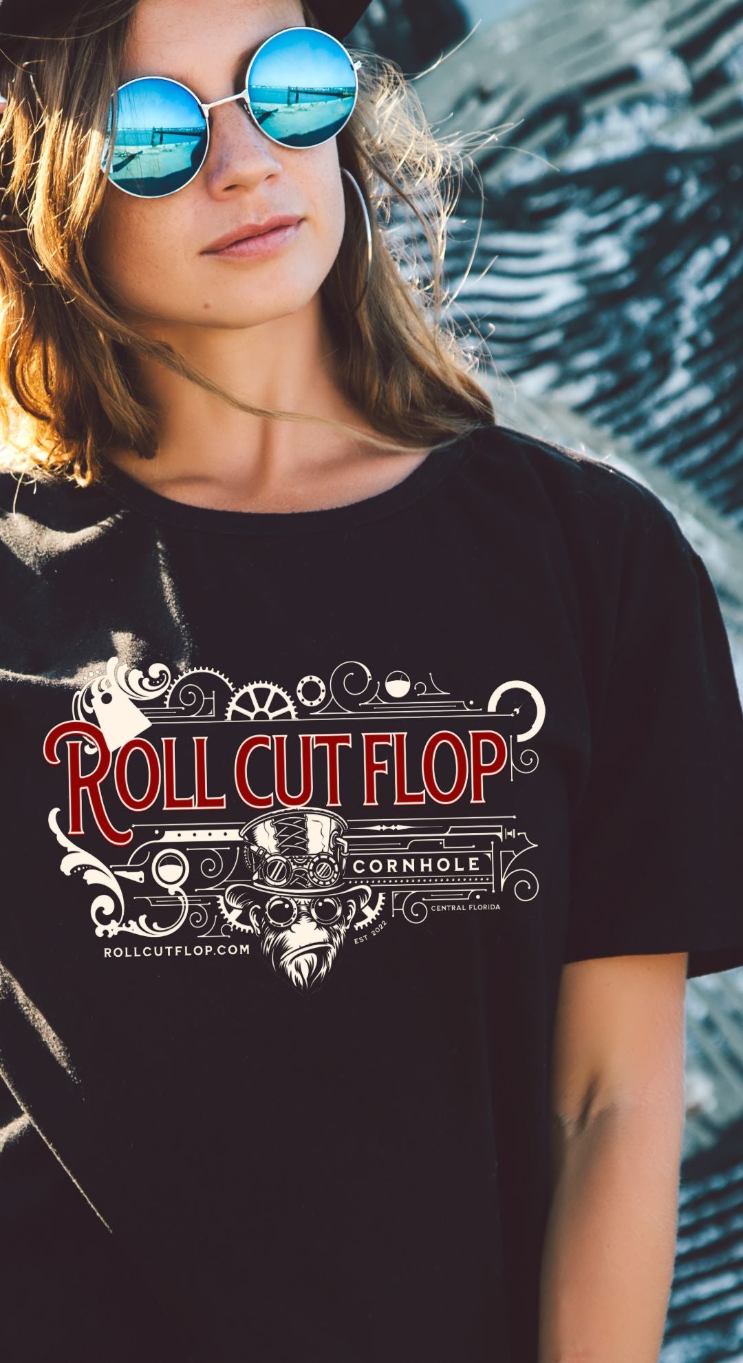 Woman in sunglasses wearing Roll Cut Flop Cornhole™ Unisex Black T-shirt - Steampunk Vintage Red Scroll